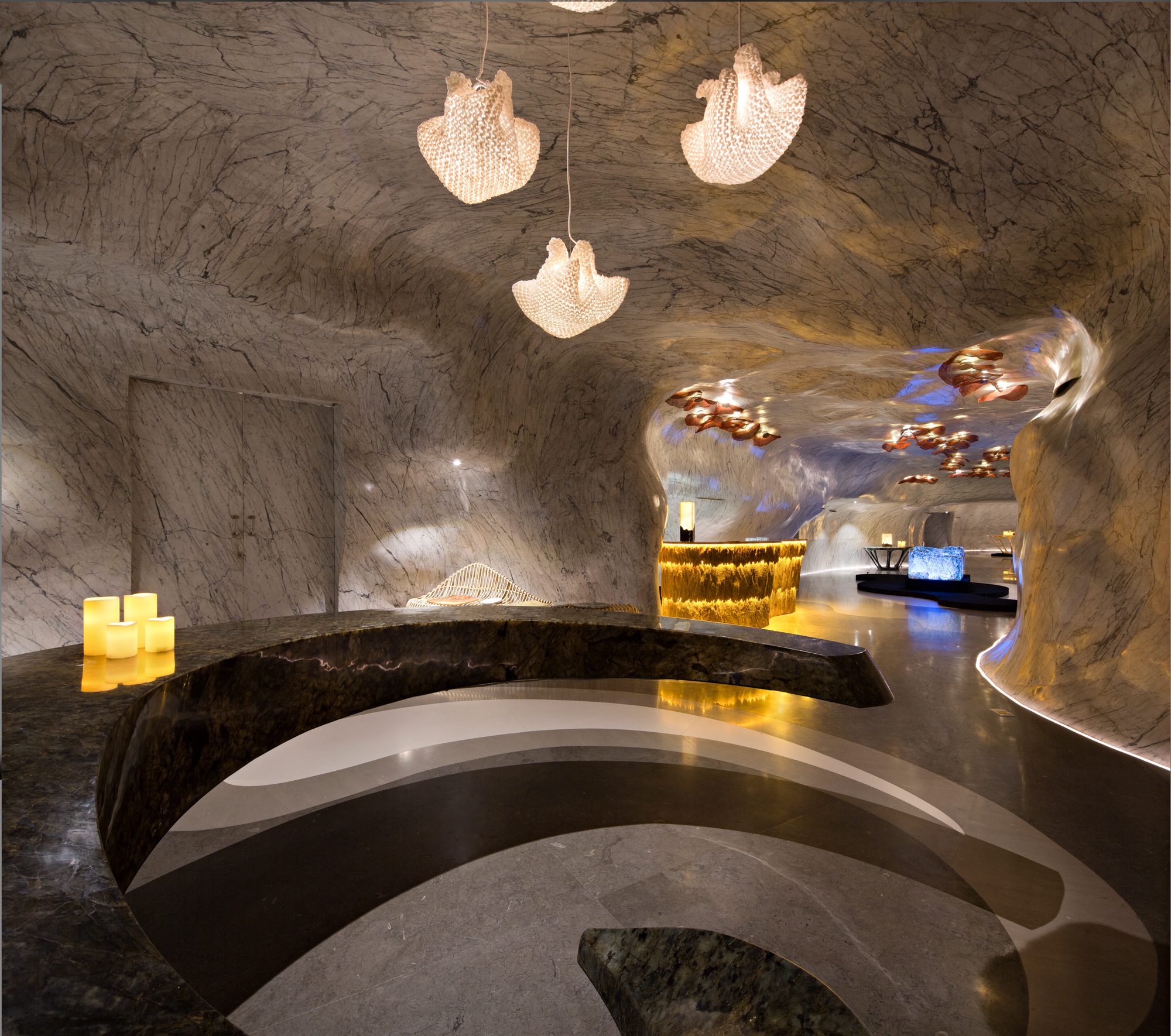 The entrance of the Singapore showroom: a dark curved counter under white pendant lamps, with the cave-like hall beyond