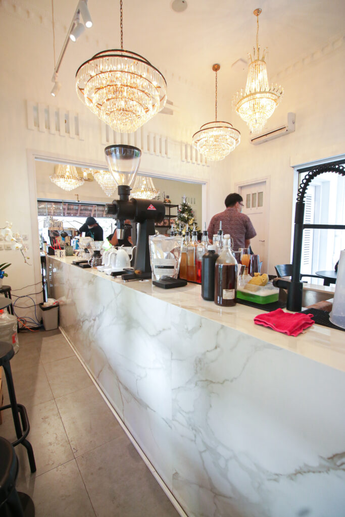 Long Blue Doors Cafe bar counter in white grey-veined Dekton Lucid, under crystal chandeliers