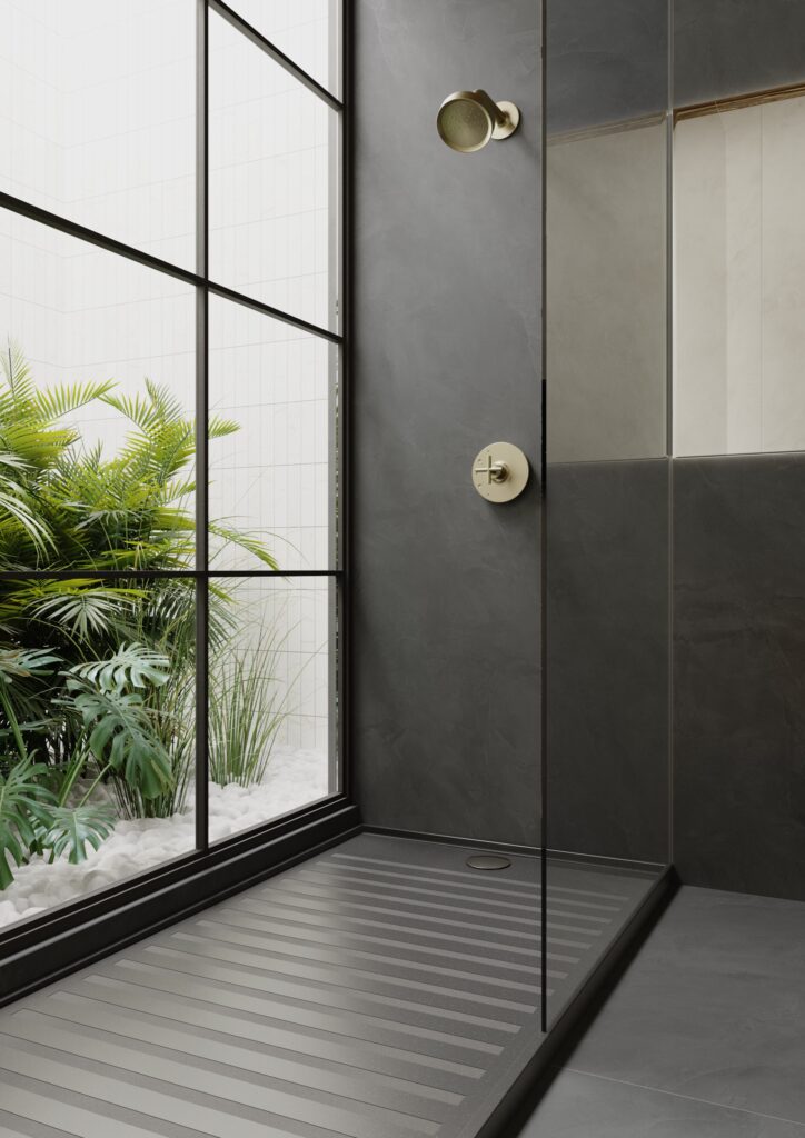 Shower clad in dark grey Dekton Kraftizen with brass fittings and a window onto a garden