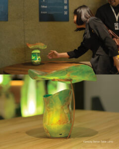 Two views of the Kantung Semar table lamp in Golden Green onyx: a visitor reaching toward it, and a close-up on a wooden table