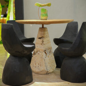Kantung Semar bistro table with a Travertine Onyx base and round teak top, surrounded by dark sculpted seats