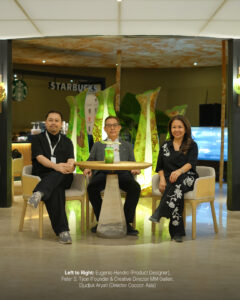 Eugenio Hendro, Peter S. Tjioe and Djudjuk Aryati seated at a stone table in front of the lit Kantung Semar lamps