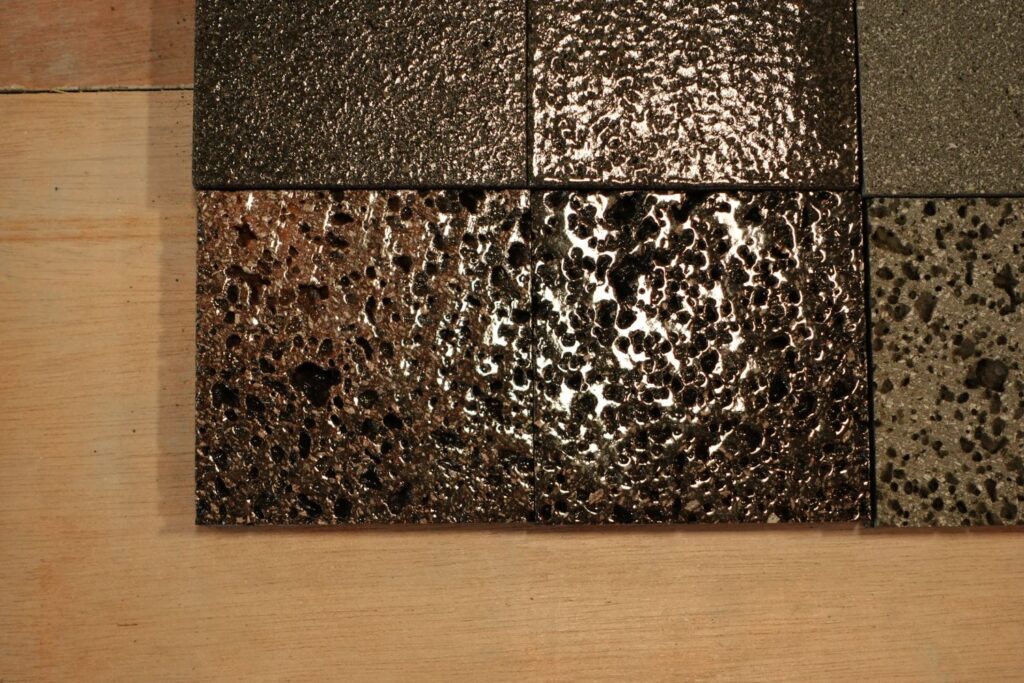 Glaze samples on lava stone tiles: the pores of the stone stay visible under the glaze.